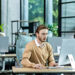 Serious and scorn-centered man in the office at work with a computer, man typing thoughtfully on